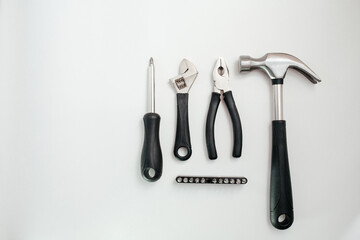 A wide range of household tools on a white background: screwdriver, adjustable wrench, pliers and hammer. View from above.