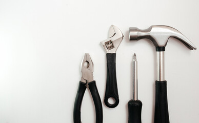 A wide range of household tools on a white background: screwdriver, adjustable wrench, pliers and hammer. Top View.