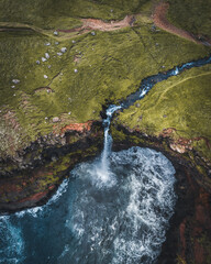 Aerial drone panorama of Mulafossur waterfall, Vagar, Faroe Islands, Denmark. Rough see in the north atlantic ocean. Lush greens during summer.
