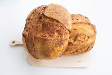 Composition in bright sunlight. Two large loaves of homemade French bread, on a wooden kitchen board