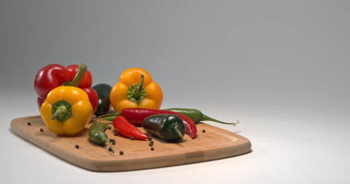 resh vegetables: orange and red peppers, green and red chili peppers, jalapeno on a wooden board on a white background.Sliced red chili pepper