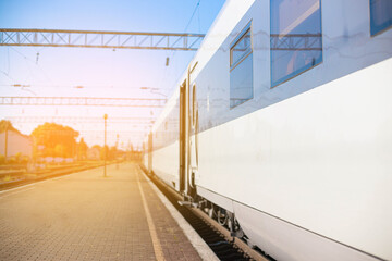 High-speed train on rails on the railway station platform on a sunny day. Modern intercity train on railway platform. Travel concept