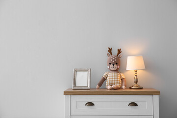 Modern white chest of drawers near light wall in child room, space for text. Interior design