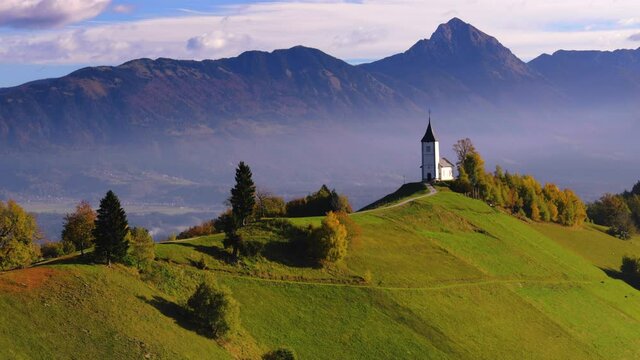 Aerial view of landscape of church of St. Primoz near Jamnik, Slovenia and Julian Alps at background