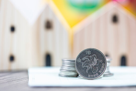 selected focus on 1 HKD Hong Kong dollar coin with blurry wooden house use as property crisis concept 