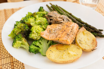 delicious dish of fried river trout fillet with garnish of broccoli, asparagus sprouts, baked potatoes and mushroom sauce