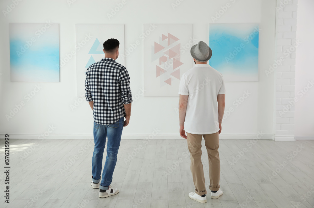 Wall mural men at exhibition in art gallery, back view