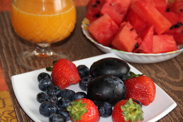 Bright juicy summer fruits and a glass of orange juice
