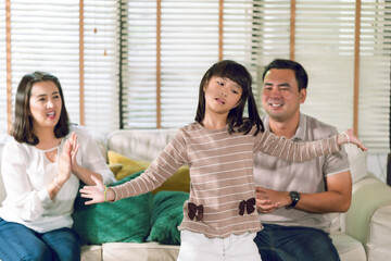Asian family doing activity  together in the house a doughter practice dancing showing her parent