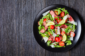 Sliced beef tagliata salad on a plate, free space