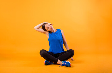 A woman in a sports uniform does a neck stretch on an orange background