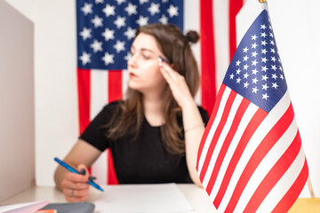 Filling out a ballot for voting in US elections. A woman sits next to an American flag and makes notes in the Bulletin. Voting in the United States. Americans vote for their candidates.