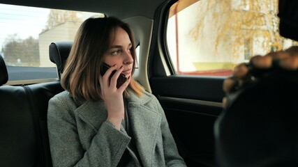 The girl in the car is talking on the phone.