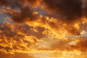 Fire sky background. Soft clouds with the hint of the sun at sunset. Many orange tones and patterns of clouds.