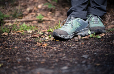 Close-up of legs and turquoise trekking shoes standing on a forest soil with space for text in the front
