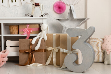 Birthday decorations - gifts, toys, balloons, garland and figure for little baby party on a white wall background.