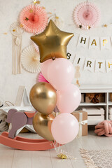 Birthday decorations - gifts, toys, balloons, garland and figure for little baby party on a white wall background.