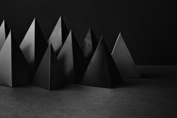 Prism pyramid objects on black gray background. Abstract geometrical figures still life composition.