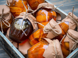 Glass jars with orange jam lie in a wooden box