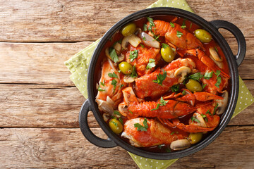 One pot Chicken Marengo with crayfish, mushrooms, olives, garlic, tomatoes and shallots close-up in a saucepan on the table. horizontal top view from above
