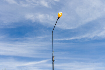 Street light beside the road illuminated during the day.