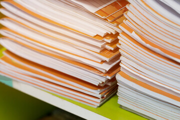 Pile of stack orange student homework book of high school students on teacher desk waiting for review In highschools in Thailand