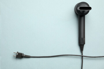 Hair dryer on light blue background, top view with space for text. Professional hairdresser tool
