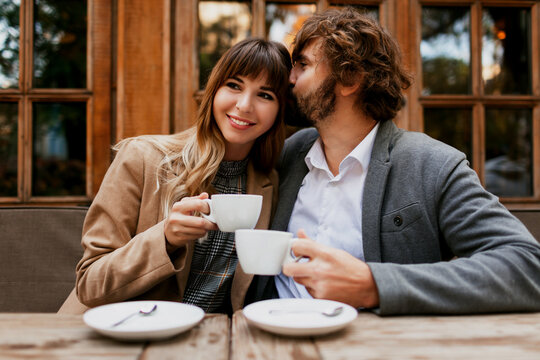 Elegant couple in love sitting in a cafe, drinking coffee, having a conversation and enjoying the time spend with each other. Selective focus on cup.