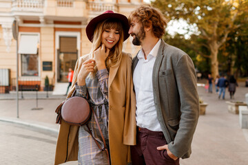 Fototapeta premium Close up portrait of amazing stylish couple in love spending romantic holidays in European city. Pretty blond woman in hat and casual dress smiling and looking on her handsome man with beard.