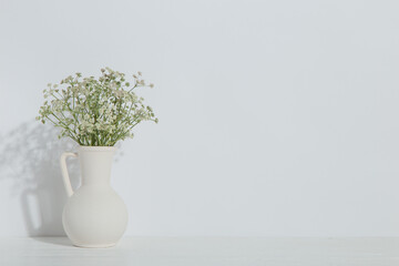 A vase with flowers on the table, on a white background. Light stylish design.