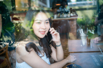 Business asian women use samrtphone sitting in coffee shop