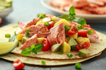Salmon fish tacos with mango, avocado, tomato, spring onion and lime. Mexican food