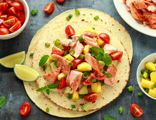 Salmon fish tacos with mango, avocado, tomato, spring onion and lime. Mexican food