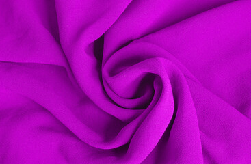 The purple fabric is rolled up in a spiral resembling a rose flower. Fabric and texture concept - close up on crumpled fabric background. Abstract background, blank template. View from above.