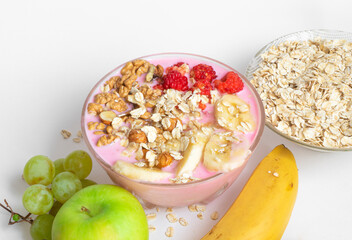 Yogurt with muesli and raspberries. Oatmeal, banana, nuts, apple, grapes on a white table close-up top view. The concept of healthy food, diet, healthy breakfast.