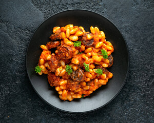 Bean and chorizo stew served in black plate with parsley