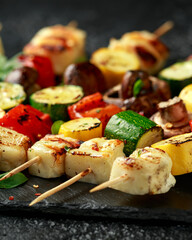 Grilled Halloumi cheese skewers with vegetables on rustic stone board