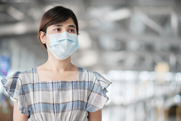 Young adult female wearing face mask in airport terminal, protection Coronavirus disease infection, Asian woman traveler ready to travel. New Normal and travel under COVID-19 concept