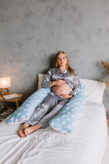 Pregnant girl lying in bed with maternity pillow