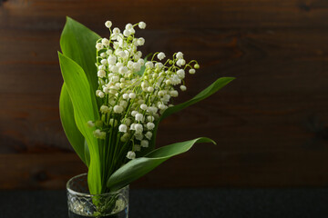 bouquet of flowers lily of the valley on dark wooden background