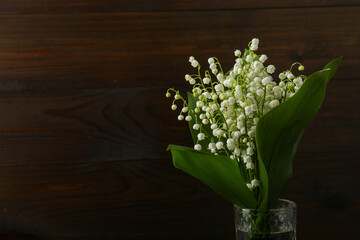 bouquet of flowers lily of the valley on dark wooden background
