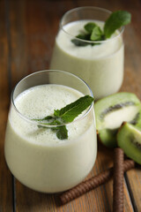 Obraz na płótnie Canvas Tasty milk shake with kiwi on wooden table, closeup