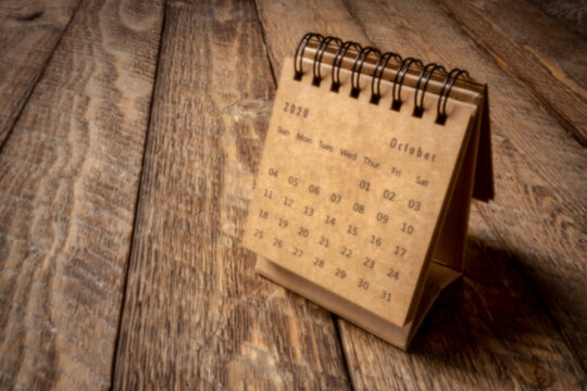 October 2020 - spiral desktop calendar on a rustic wood table, time and business concept, soft focus image shot with a lensless pinhole camera