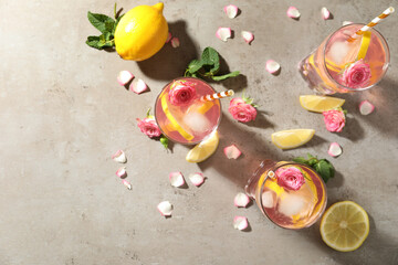 Fototapeta na wymiar Delicious refreshing drink with rose flowers and lemon slices on light grey table, flat lay