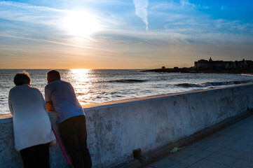 Elderly couple watching sunset at edge of coast