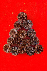 Chrismas red background with christmas tree made of pine cones and space for text. Happy new year and Merry Xmas post card.