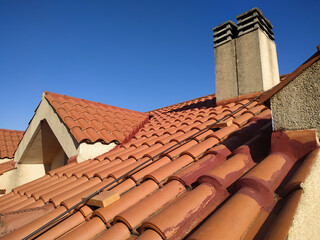 Tiles and chimney on the roof of a residential building attic over blue sky