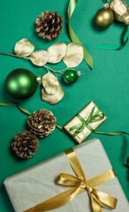 weihnachtliche Dekoration mit Geschenken, Zuckerstange, Geschenkband Zapfen, Sternen, Gräsern und Eukalyptus in gold auf grünem Untergrund