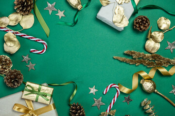 weihnachtliche Dekoration mit Geschenken, Zuckerstange, Geschenkband Zapfen, Sternen, Gräsern und Eukalyptus in gold auf grünem Untergrund