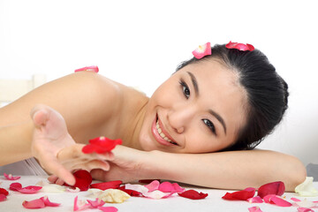 Naklejka na ściany i meble Young beautiful Southeast Asian woman beauty fashion makeup light grey white background resting on hand flower patellas all over eyes open